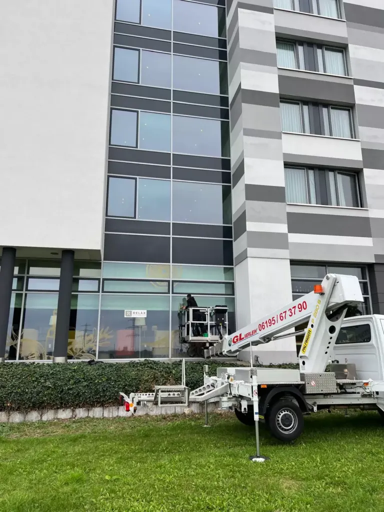 Arbeiter reinigt mit einer Hubbühne die Glasfront eines Hochhauses