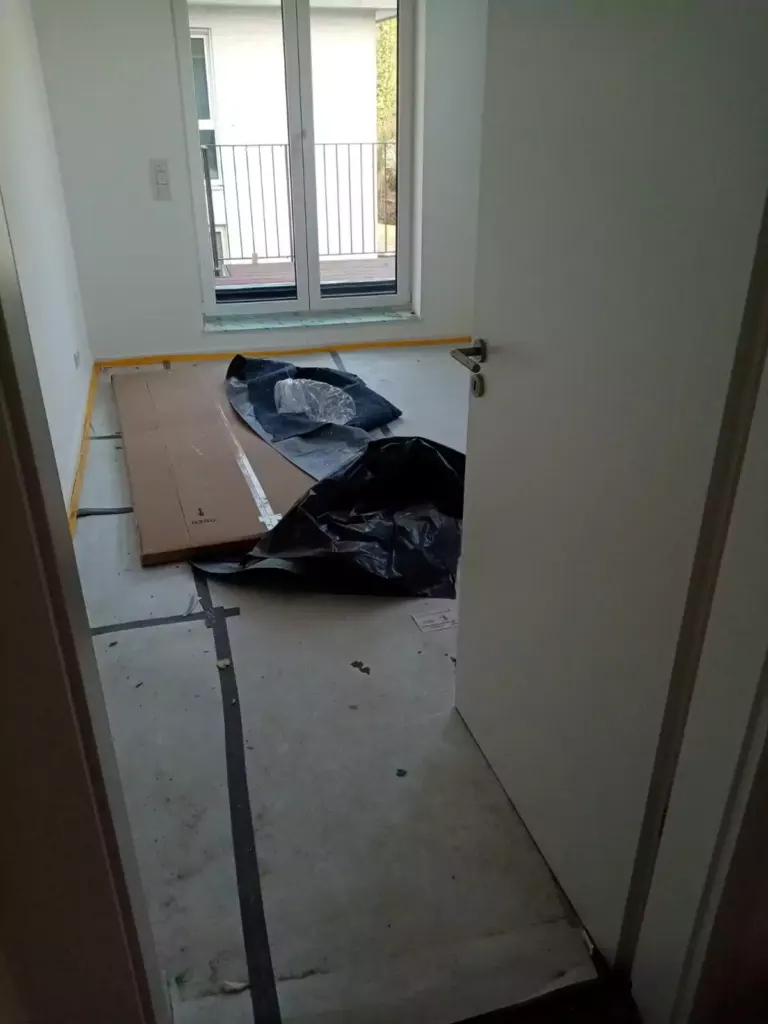 Leeres Zimmer mit Verpackungsmaterial und Müllsäcken beim Ausräumen