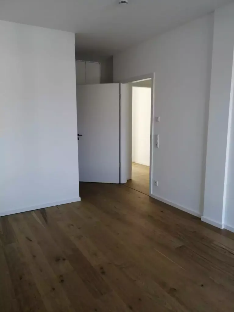 Frisch gereinigtes leeres Zimmer mit Parkettboden im Neubau