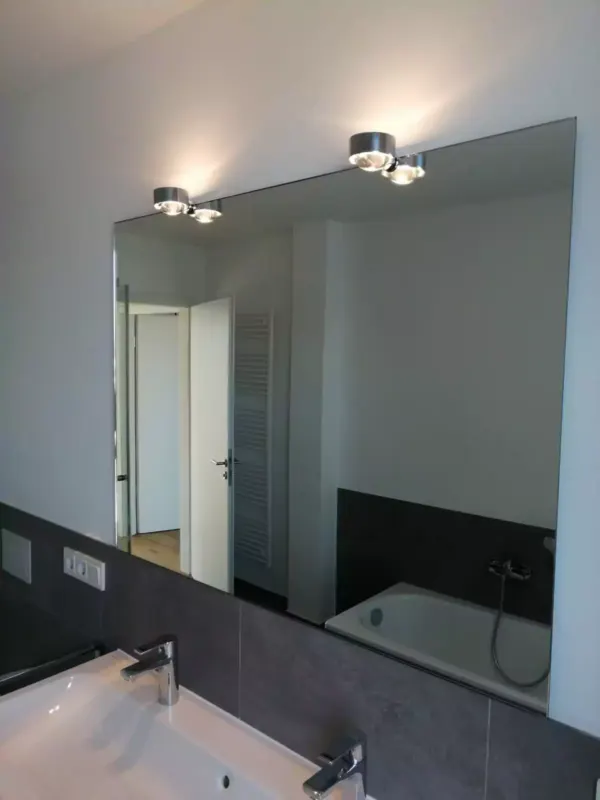 Modernes Badezimmer mit großem Spiegel und dunklen Fliesen