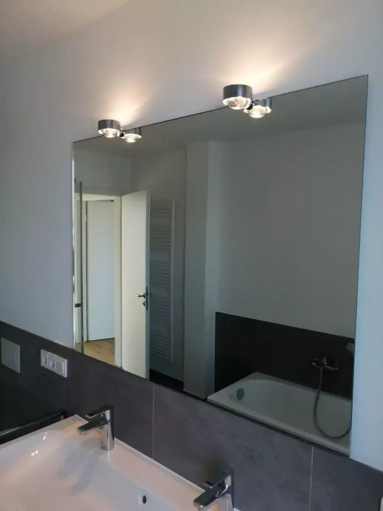 Modernes Badezimmer mit großem Spiegel und dunklen Fliesen