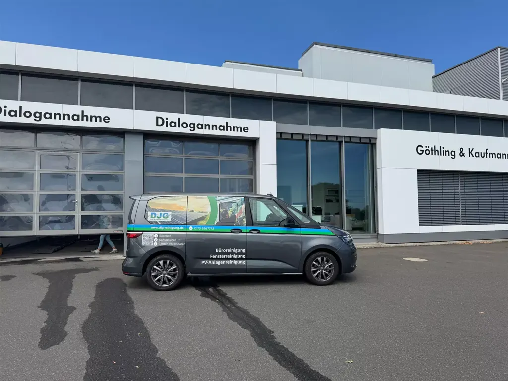 Grauer Firmentransporter auf einem Parkplatz vor einem Autohaus