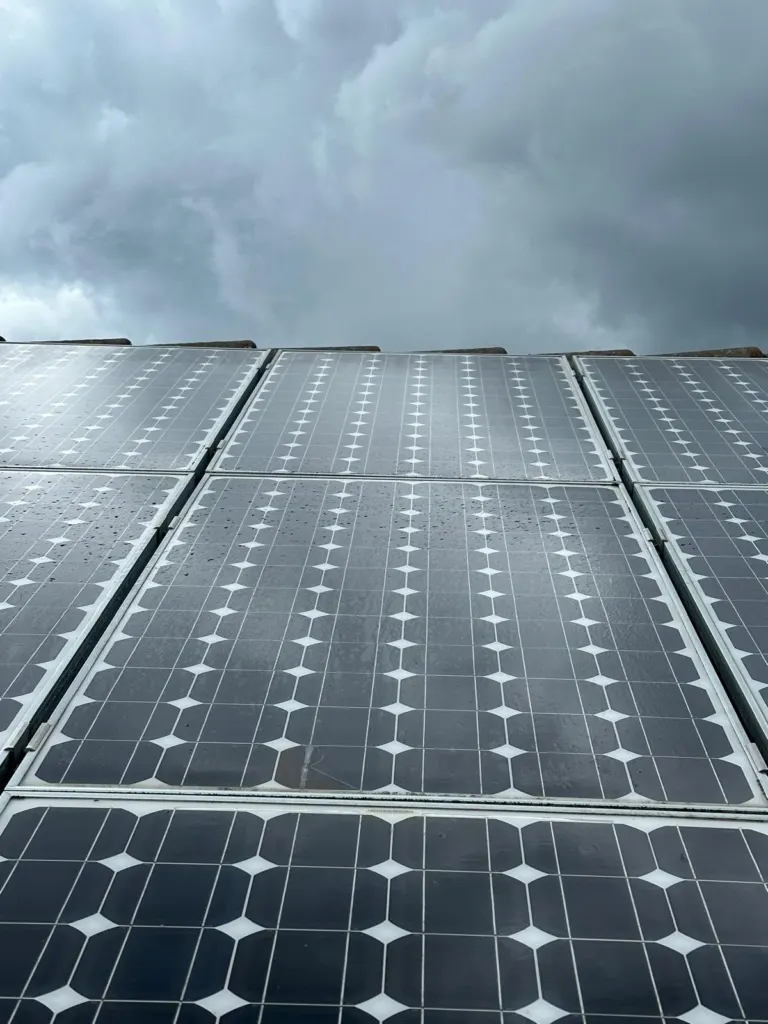 Frisch gereinigte, nasse Photovoltaikmodule auf einem Dach unter bewölktem Himmel